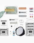 A bridal emergency kit and beauty relief set laid out on a white background, including a mini mirror, face wash, facial tissues, facial adhesive, facial pain relief, bobby pins, double-sided tape, cotton swabs, and a mint green neck pillow.
