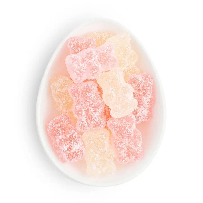 Several bubbly bears by Sugarfina are featured in a ceramic white dish white, pink, and orange color on a white background. 