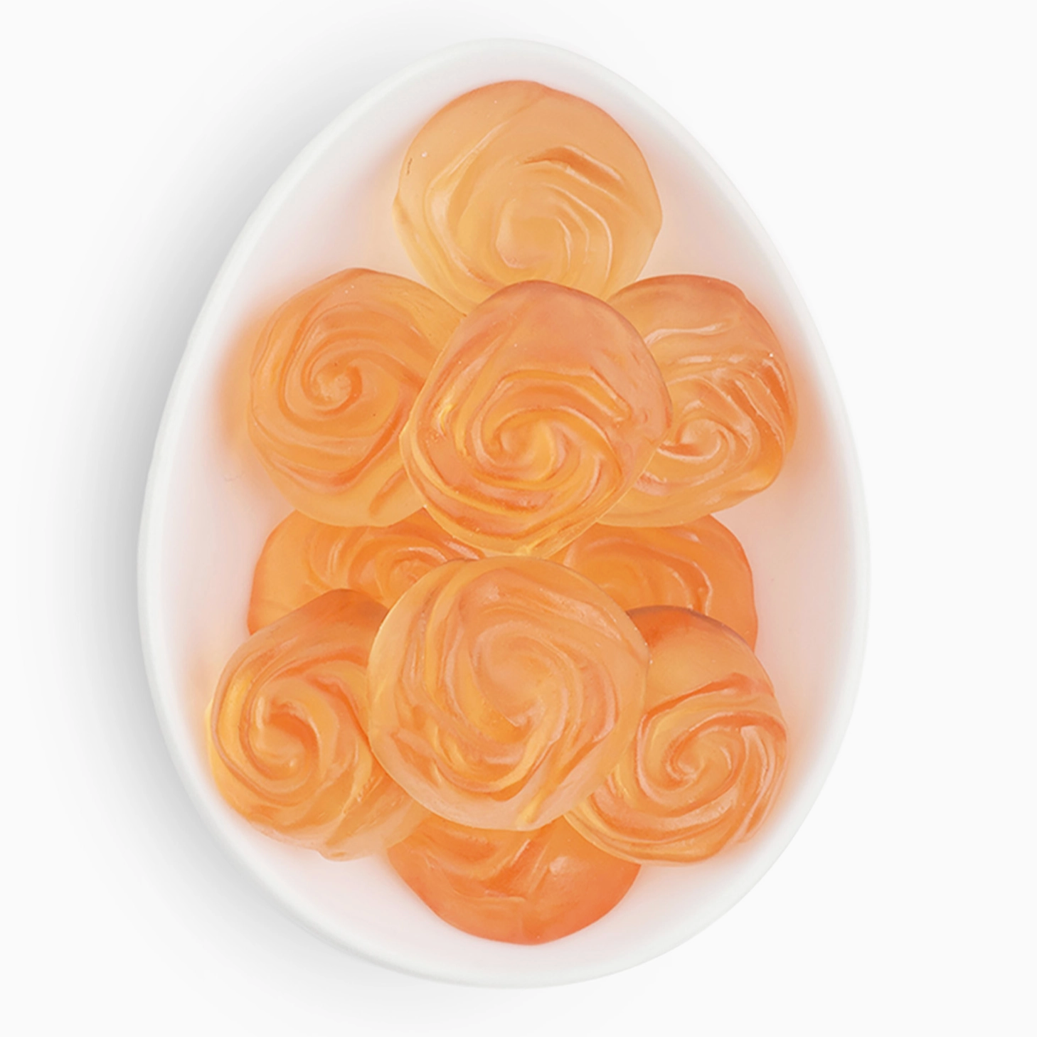 Orange rose-shaped candies on a white plate with a white background
