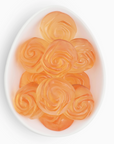 Orange rose-shaped candies on a white plate with a white background