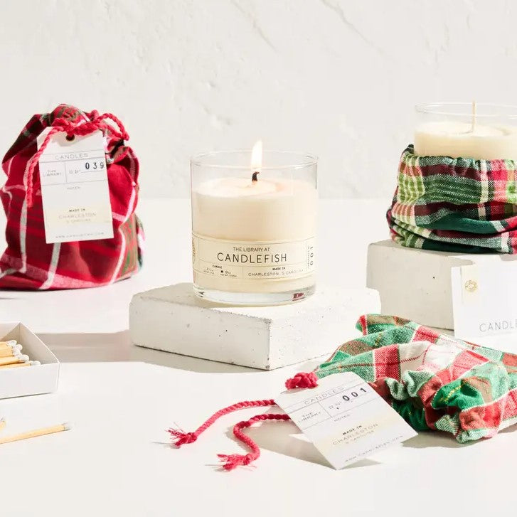 Image shows in a white background two of the candlefish holiday candle number 39 . Which comes in a holiday bag with green read and white color stripes. 