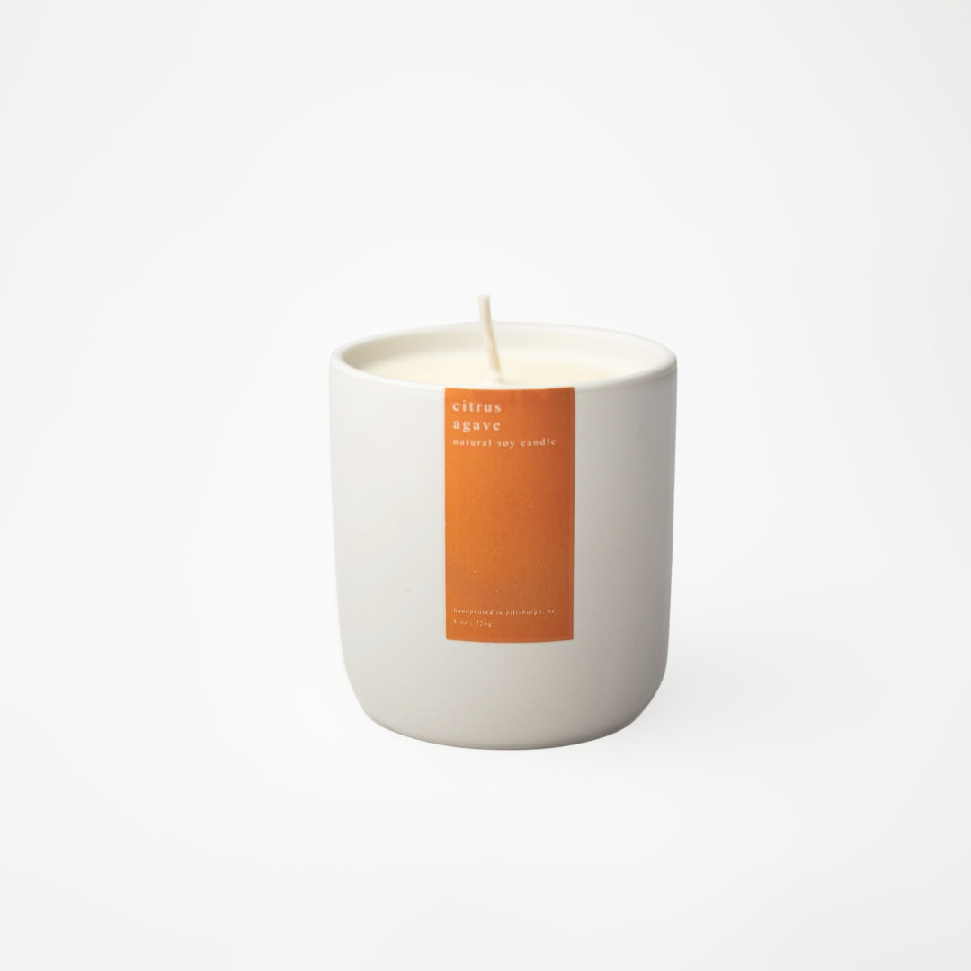 White candle with an orange label on a white background