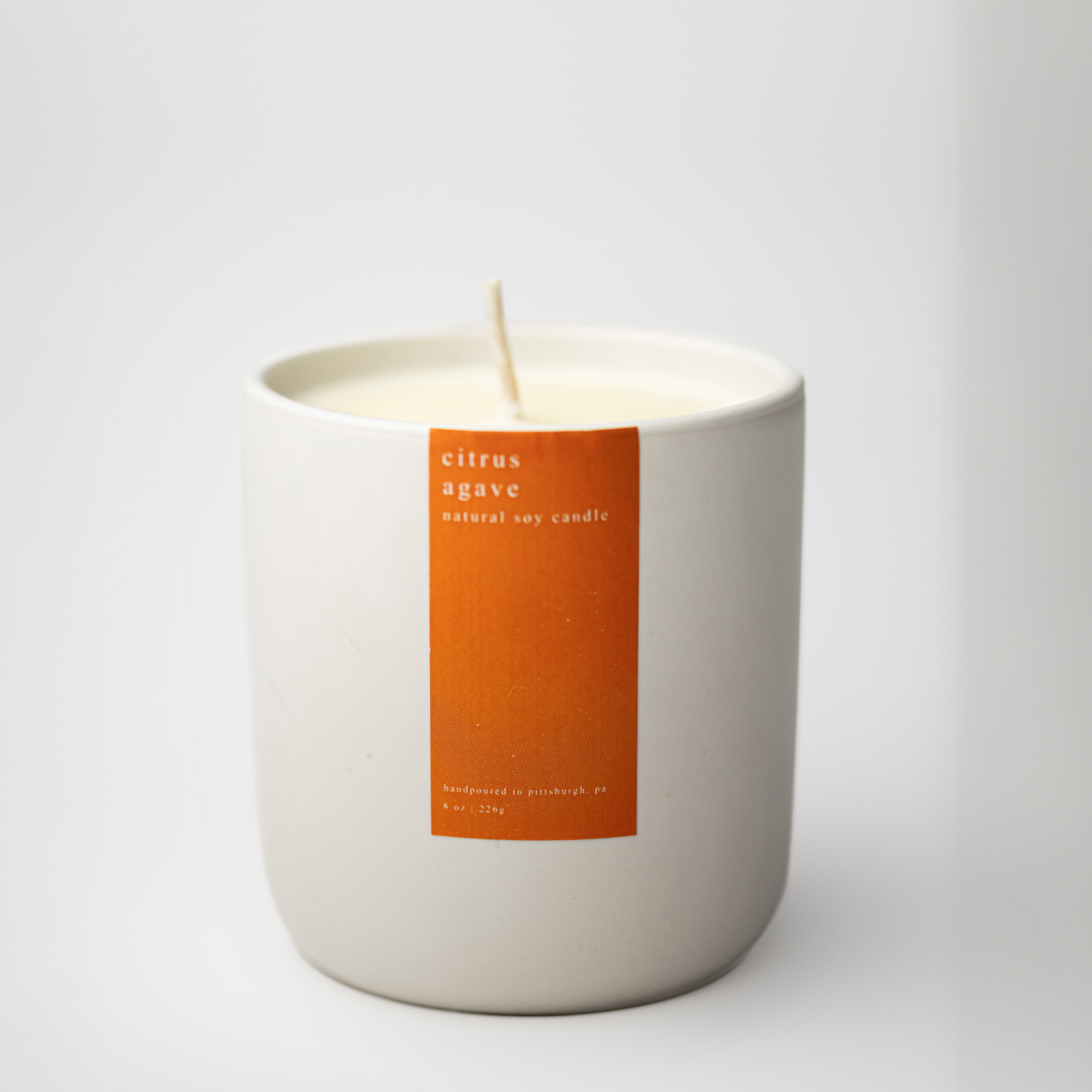 White candle with an orange label on a white background