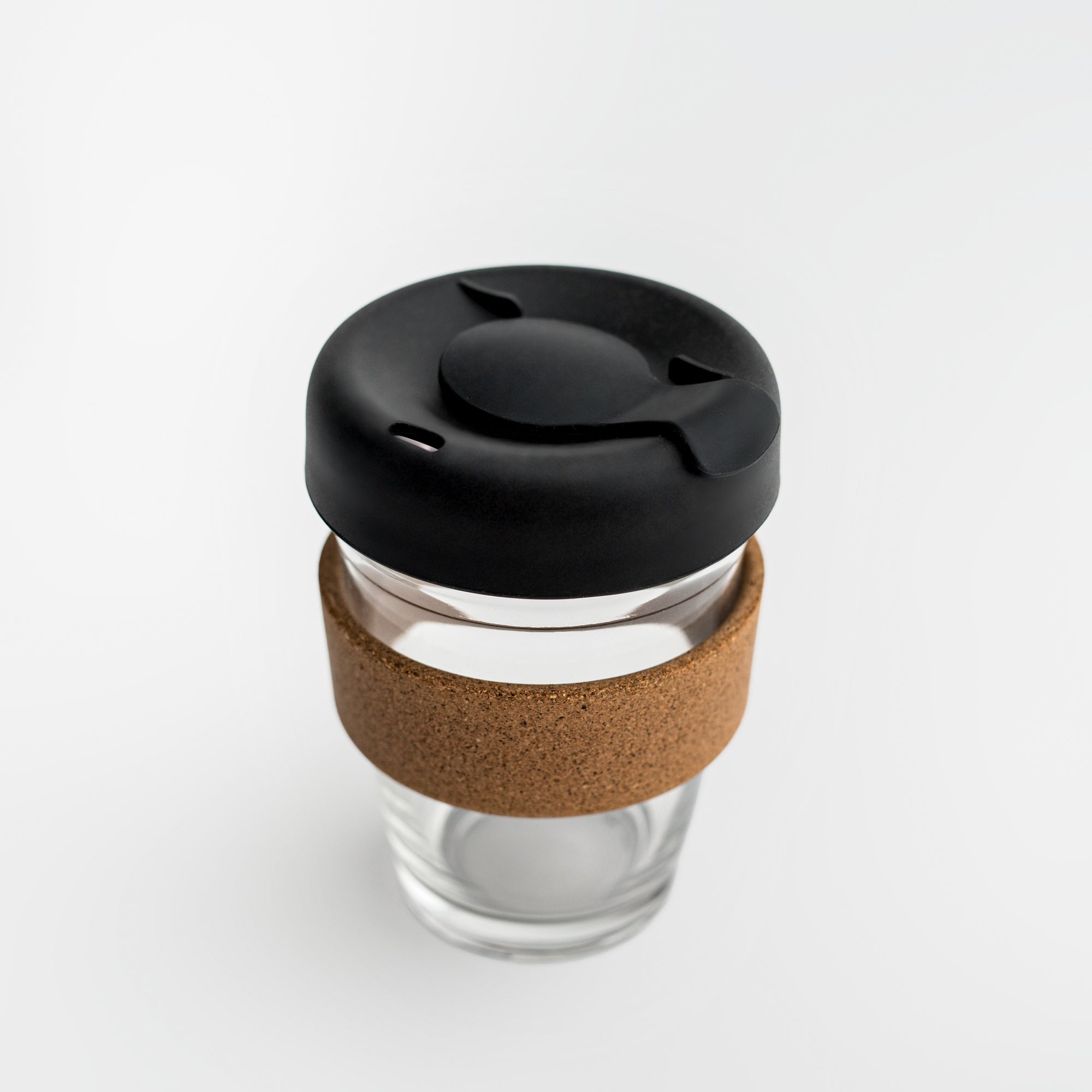 Clear tumbler with cork holder featured transparent tumbler with cork holder and black lid on a white background. 
