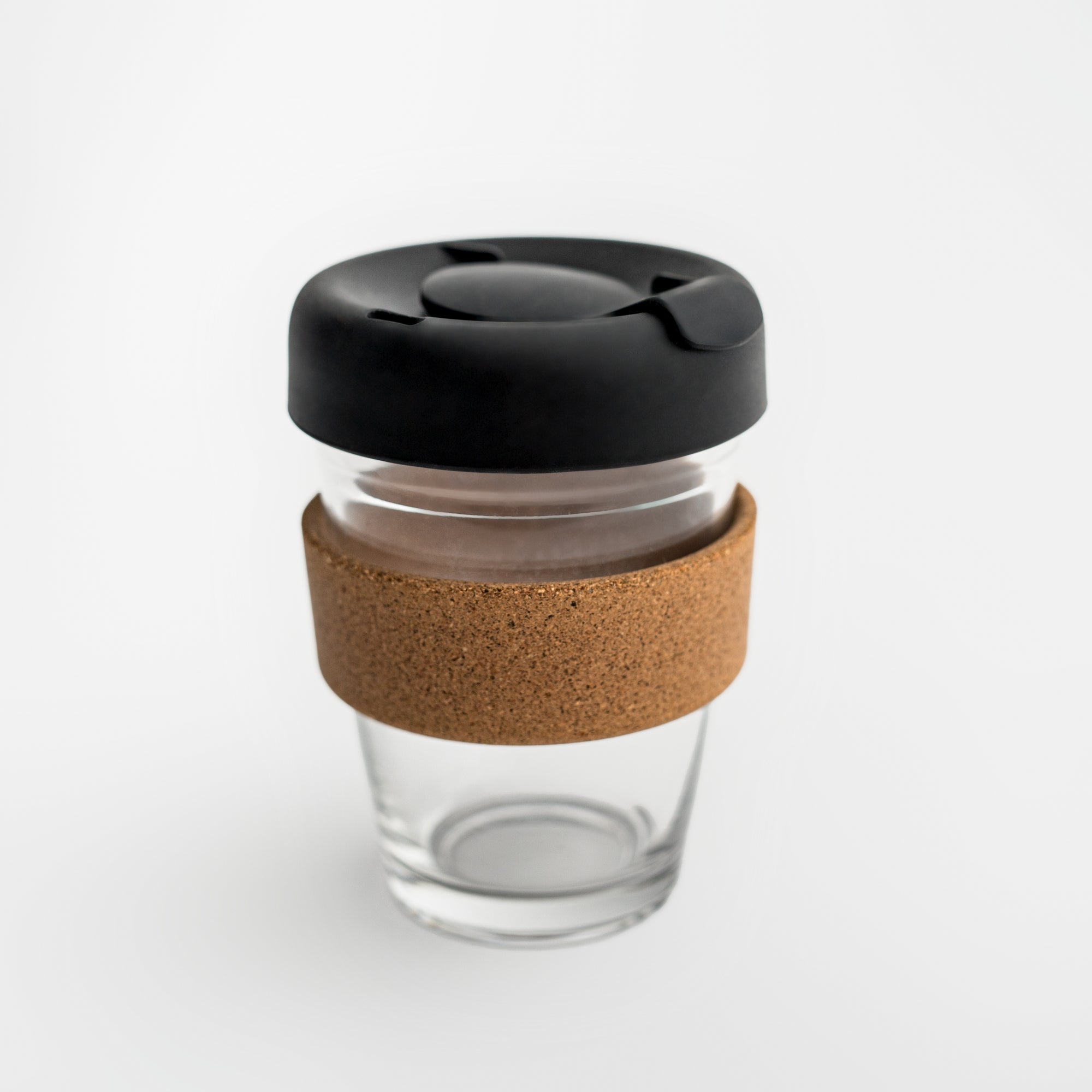 Clear tumbler with cork holder featured transparent tumbler with cork holder and black lid on a white background. 