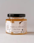 clover Honey form Anellebees, picture of it's container transparent hexagon shaped jar with white label that has images of honey combs and a honey drizzle pouring a bit of honey. The jar shows the honey inside in its yellowish caramel color.  