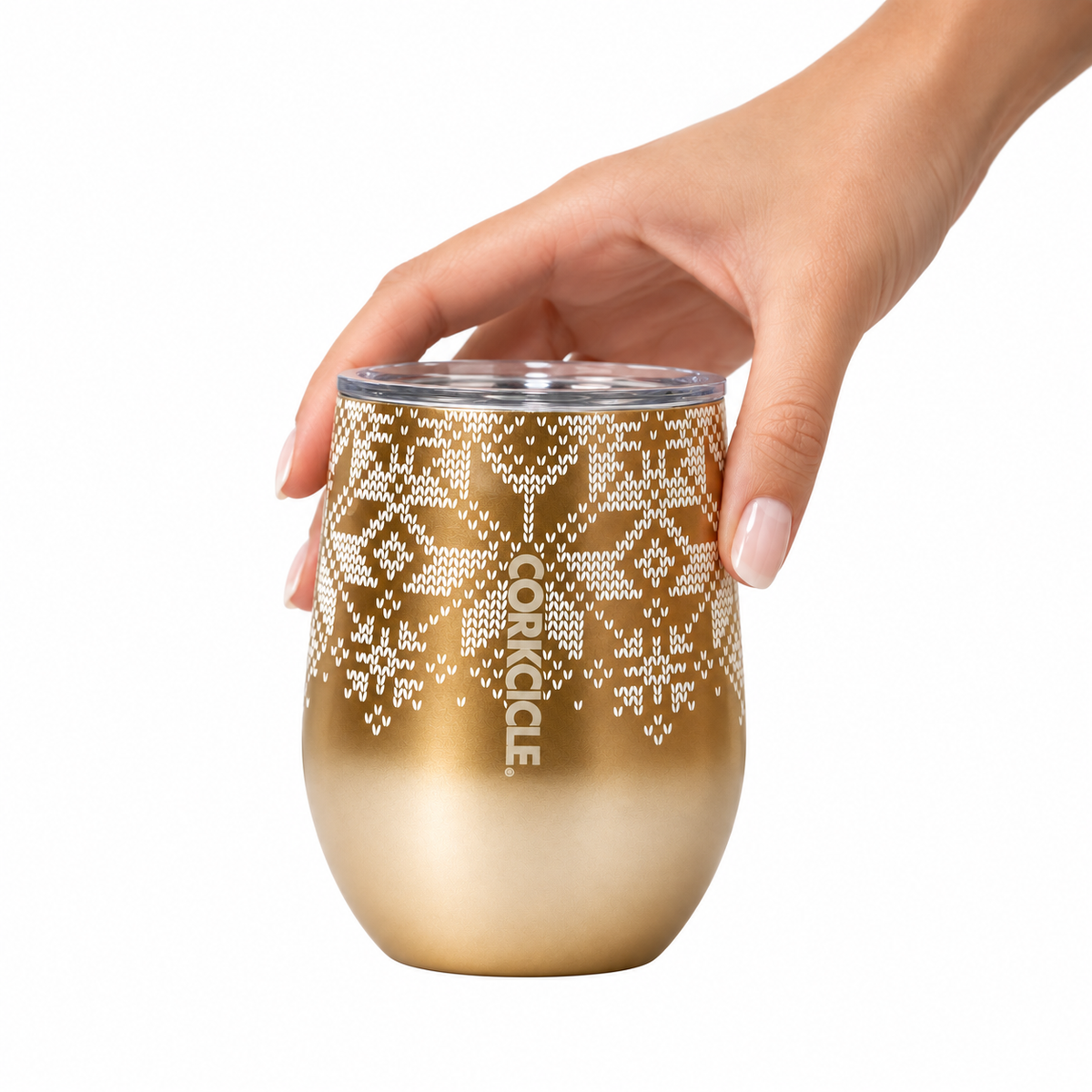 A hand holding a gold stemless wine tumbler with a white snowflake pattern and the brand name 'CORKCAGE' printed vertically, set against a plain white background.