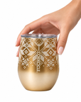 A hand holding a gold stemless wine tumbler with a white snowflake pattern and the brand name 'CORKCAGE' printed vertically, set against a plain white background.