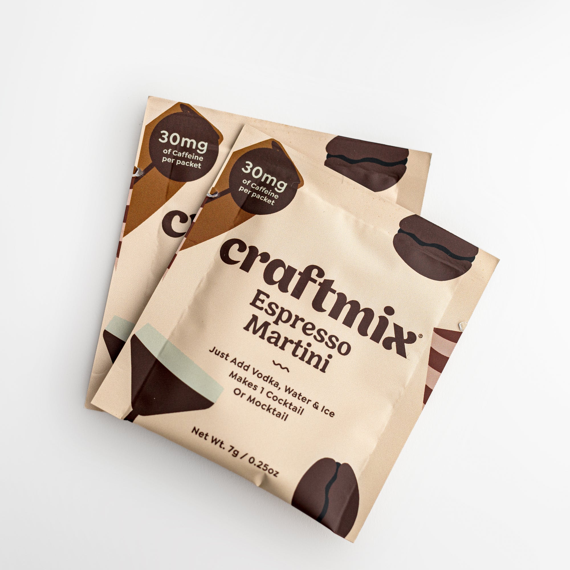 Craftmix espresso martini featured the two  packets. The packets are rectangular with rounded corners, made of a light beige material. Prominently displayed on the packets are the words "craftmix" in a bold, modern font, and "Espresso Martini" in a stylish script below. There's also the claim "30mg of Caffeine per packet" in a brown hexagonal label. The design also incorporates subtle illustrations of coffee beans and a cocktail glass. On a white background.