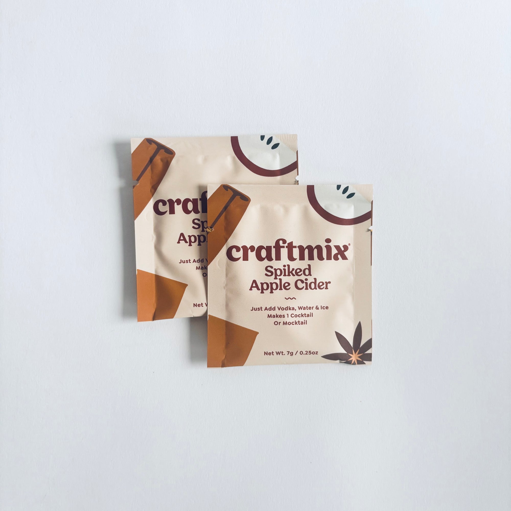 Two craftmix spiked apple cider mix packages in beige and brown details with brown lettering in a white background. 