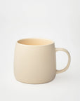Cream ceramic coffee mug with a smooth matte finish, simple rounded handle, and minimal design, isolated on a white background.