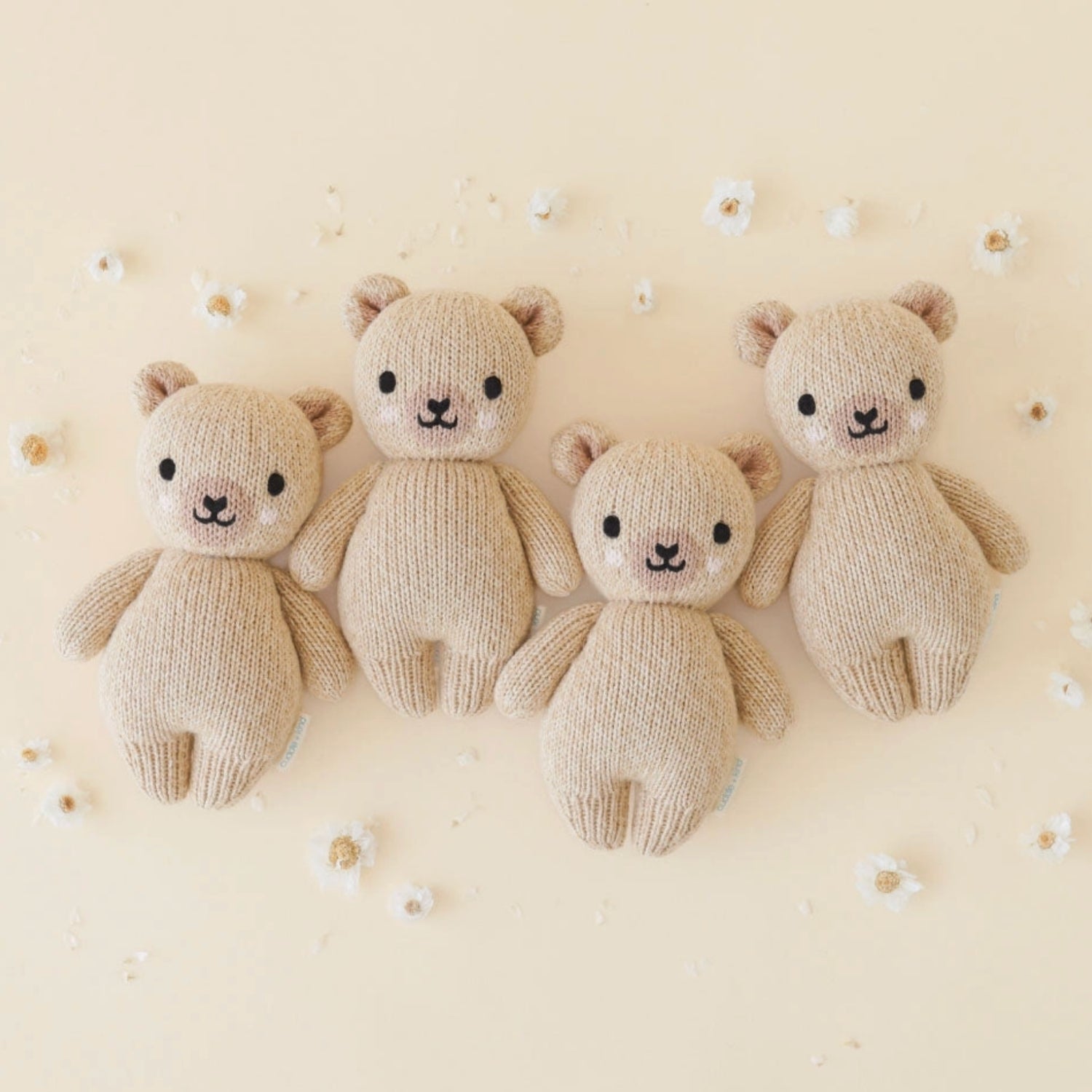 Multiple Handcrafted Cuddle + Kind Baby Bear plush in soft neutral knit fabric, sitting upright on a clean white background, featuring stitched facial details and a cozy handmade texture.