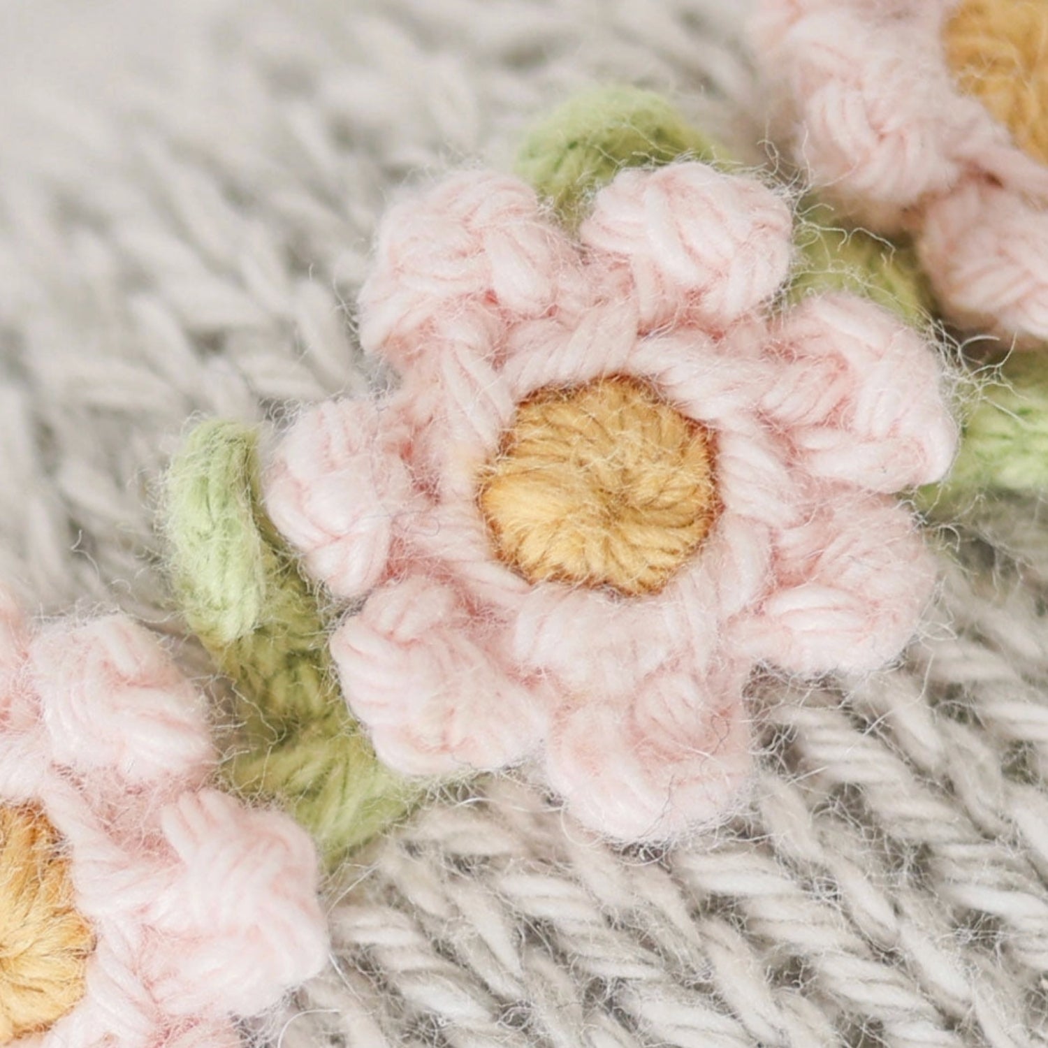 Close-up detail of a Cuddle + Kind Baby Elephant plush wearing a rose headband, showing the soft knit texture, stitched facial features, and the delicate fabric rose accent against a clean white background.