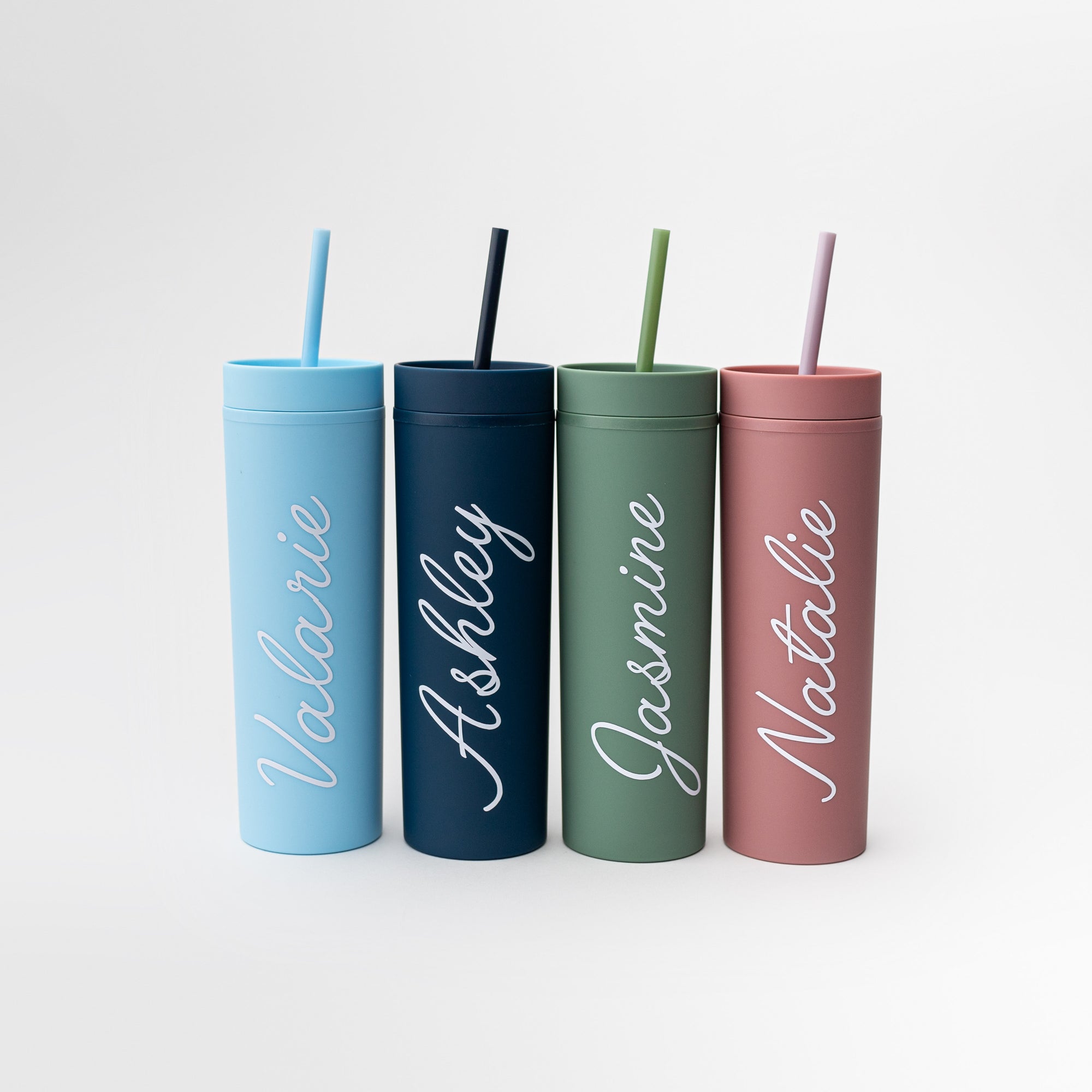 Our custom tumblers with straw shown in the four colors they come light blue, navy, green and rose. Personalized in white lettering with the names Valerie, Ashley, Jasmine and Natalie on a white background.  