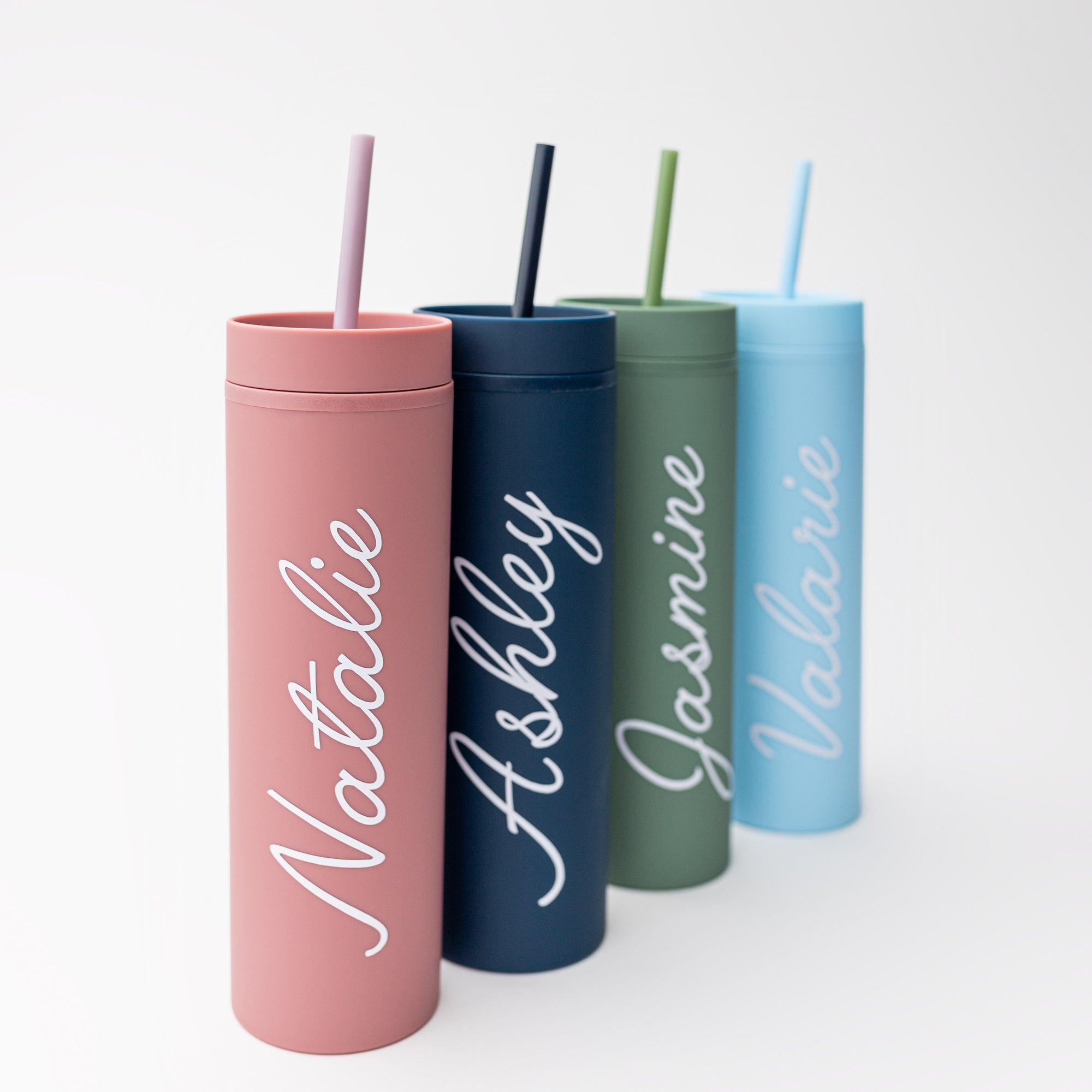 Our custom tumblers with straw shown in the four colors they come light blue, navy, green and rose. Personalized in white lettering with the names Valerie, Ashley, Jasmine and Natalie on a white background.  