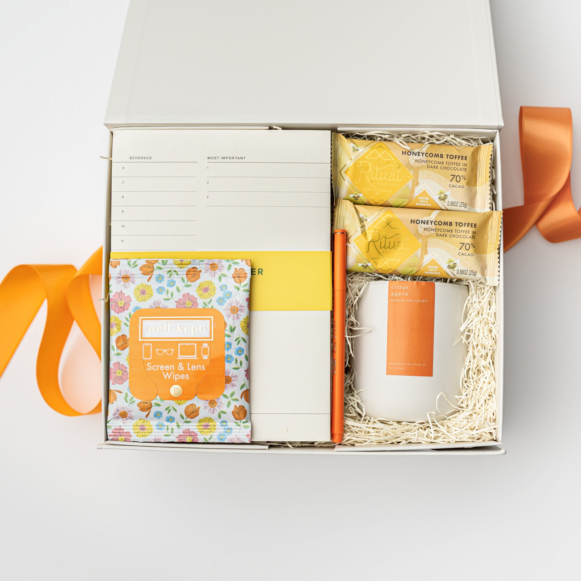 Gift box with stationery items and a candle on a white background