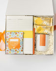 Gift box with stationery items and a candle on a white background