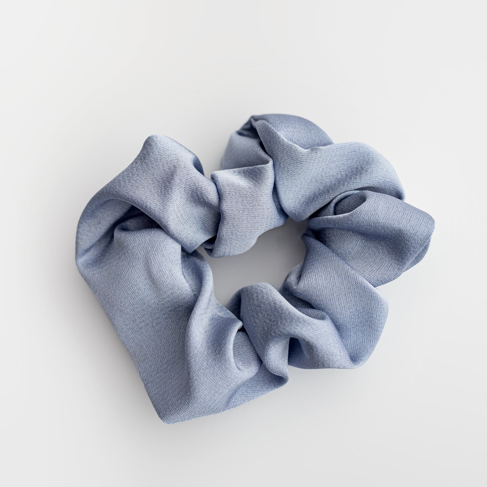 Dusty blue scrunchie on a white background showcased. 