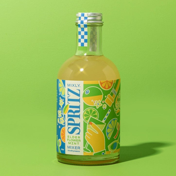 Elderflower mint spritz mix is featured in its transparent bottle with silver lid showing the green liquid inside with green and blue label graphics on a green background. 