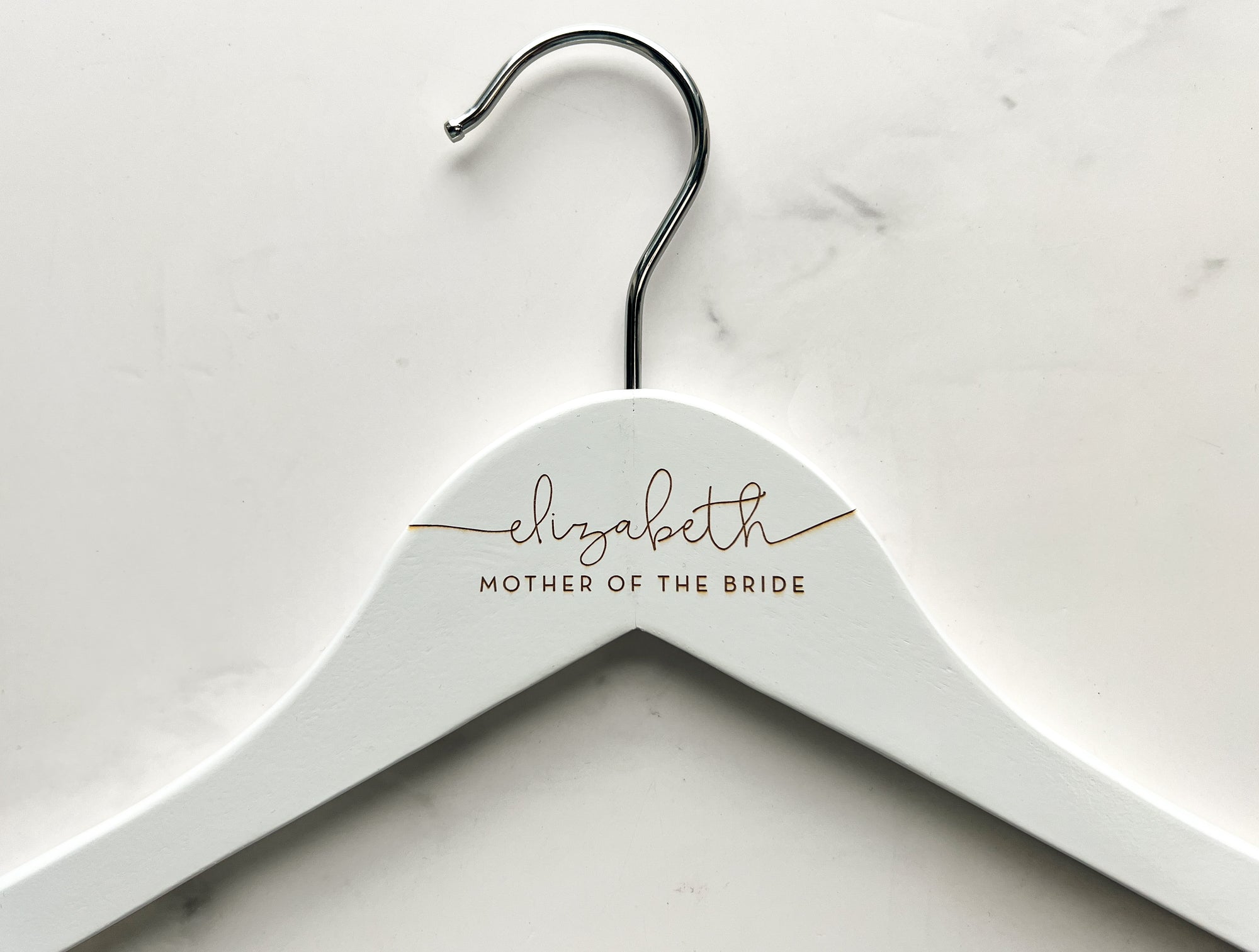 Engraved bride hanger in white personalized Elizabeth - mother of the bride on a marble-like background.