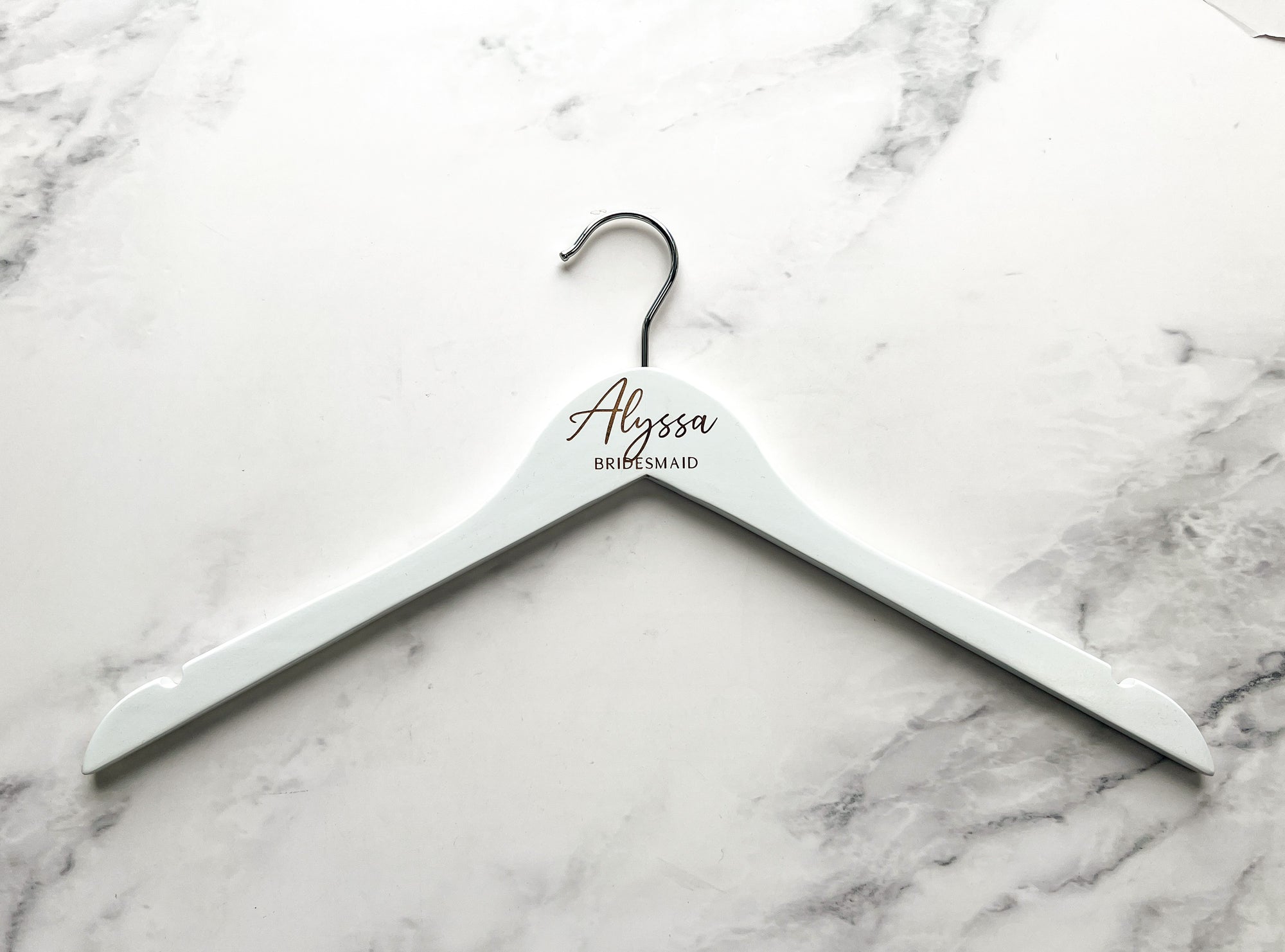 Engraved bride hanger on white personalized Alyssa bridesmaid on a marble like background. 