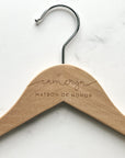 Close up image of natural engraved brie hanger that is personalized Cameryn matron of honor on a marble like background.