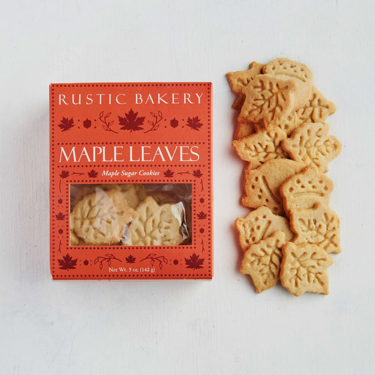 Rustic Bakery Maple Leaves sugar cookies shown next to their red packaging box on a white background.