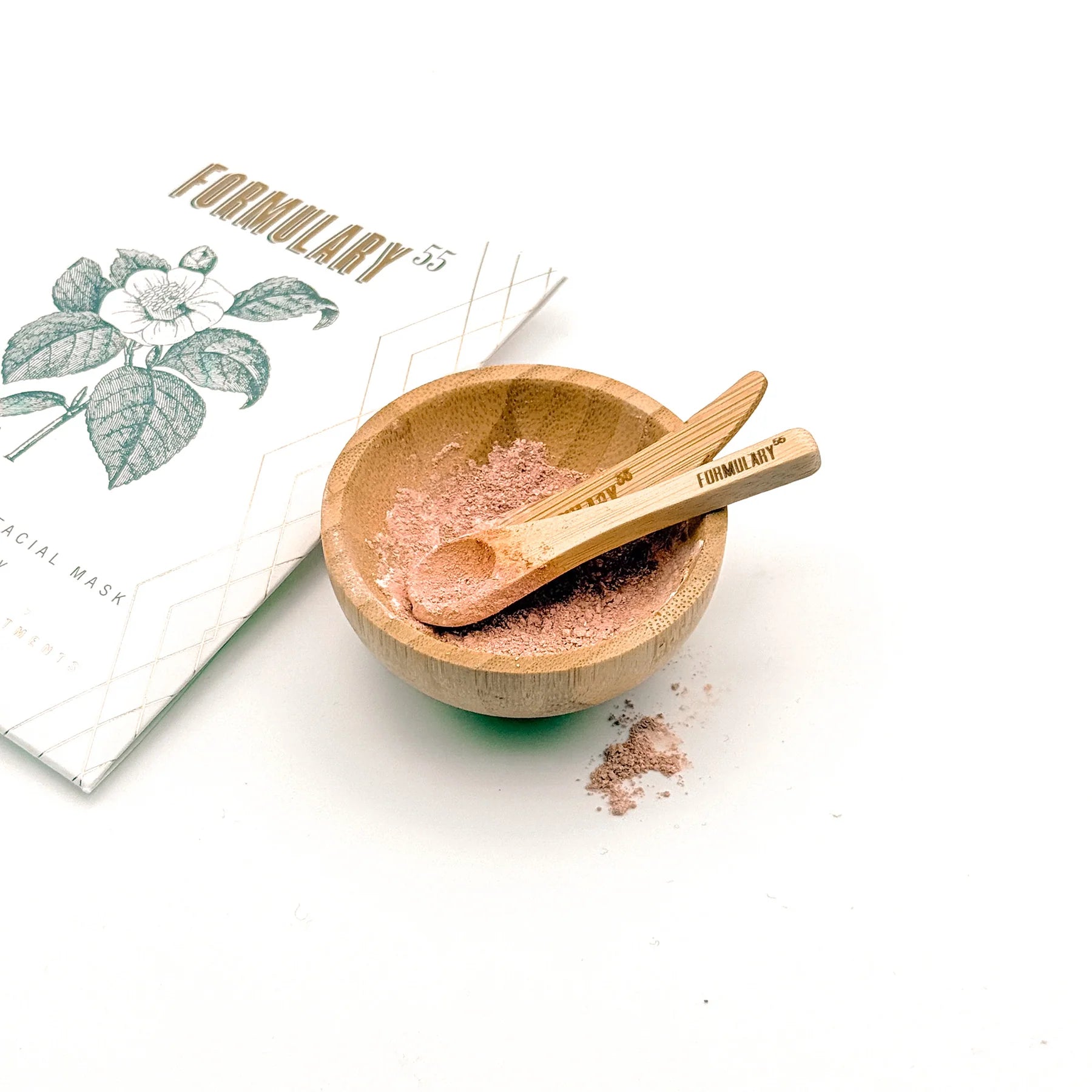 Formulary 55 organic facial mask shown both in its packaging and mixed in a bamboo bowl, accompanied by a bamboo spatula and spoon, displayed on a white background.