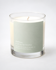 A glass jar candle with cream-colored wax and a single wick, featuring a muted sage green label that reads 'fresh laurel COUNRSIDE' and 'BEFORE THE WORLD WAKES UP'.