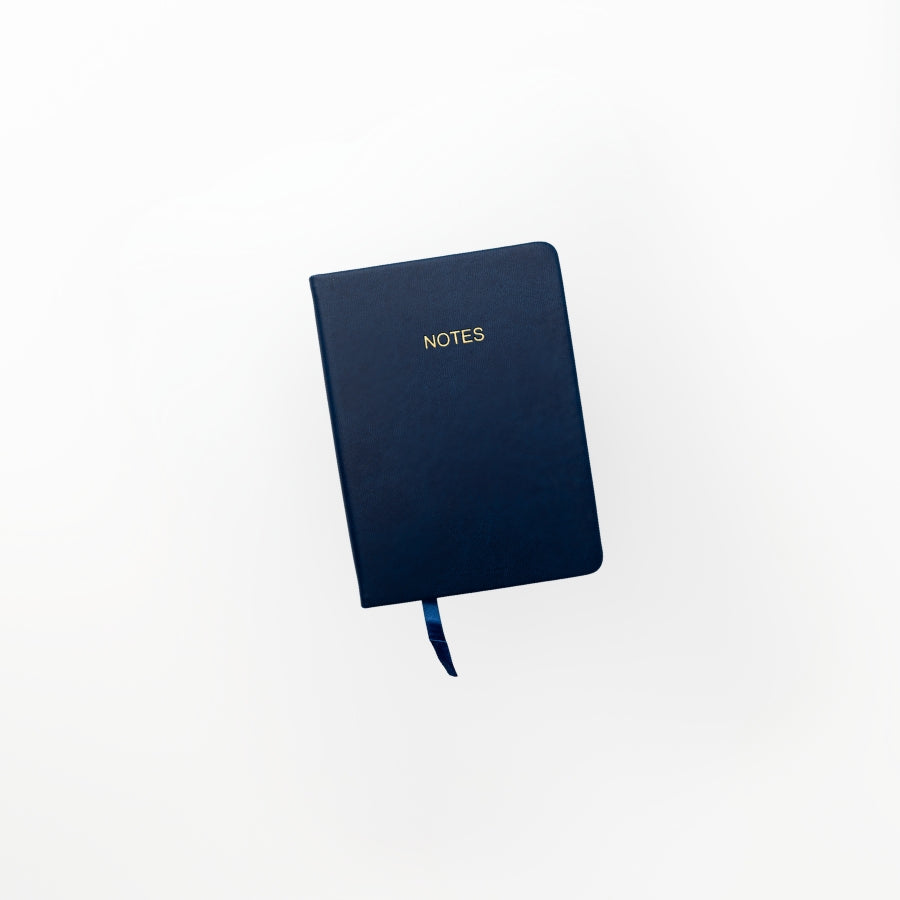 Navy softcover pocket notebook with a flexible cover and lined pages, displayed on a clean white background.