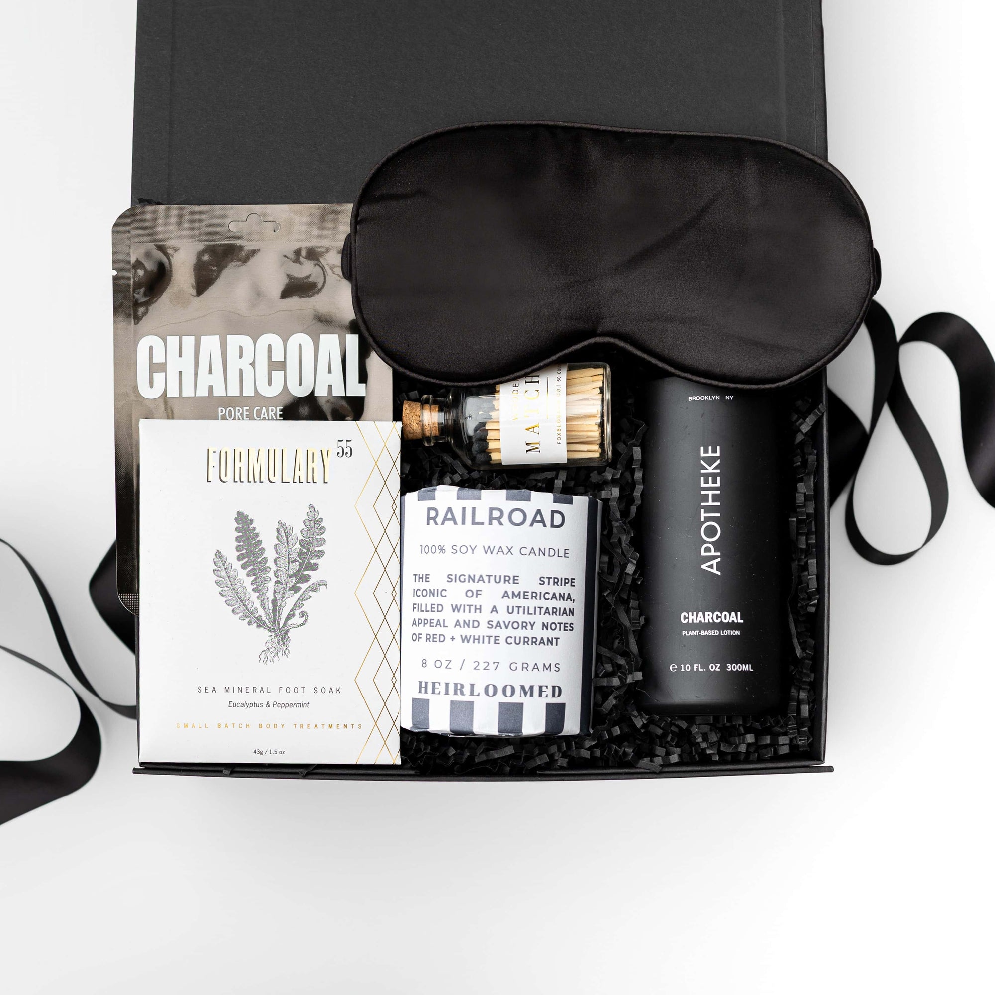Gift set with sleep mask, charcoal soap, and other items on a white background
