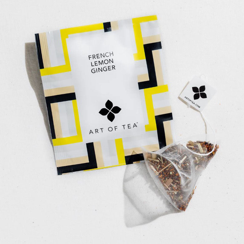 French Lemon Ginger Tea sachet, image shows the sachet that has a background image of geometrical lines of yellow, gray, white, and black with white label that shows the product details in black lettering. 