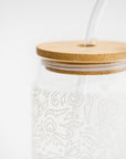 Close-up image of glass  straw tumbler with a floral design with the bamboo lid  on a white background. 