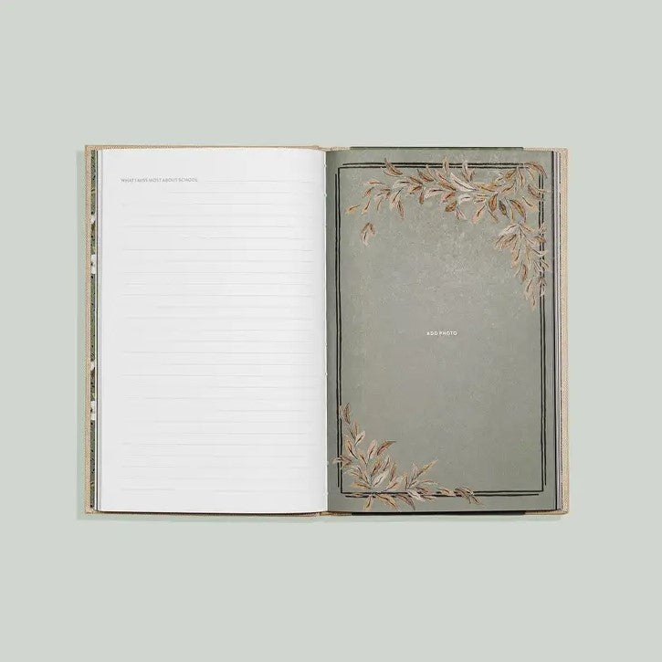 Grandma's Story memory keepsake and journal book. An open, lined journal, featuring a muted, greyish-green background framed by delicate, brown-toned leaf illustrations.