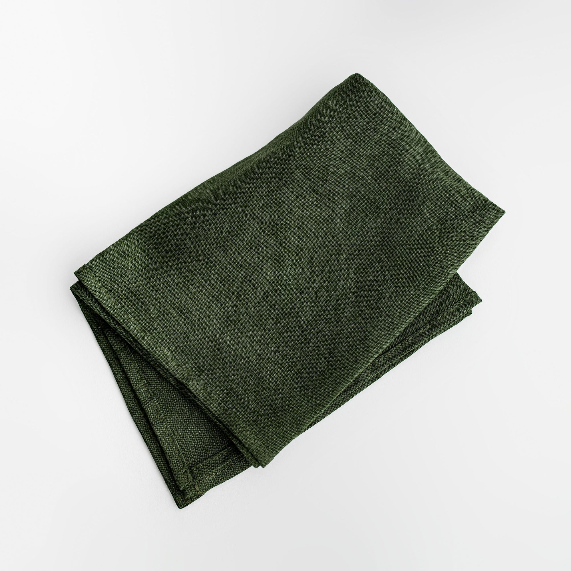 A green linen kitchen towel is featured, folded on a white background. 