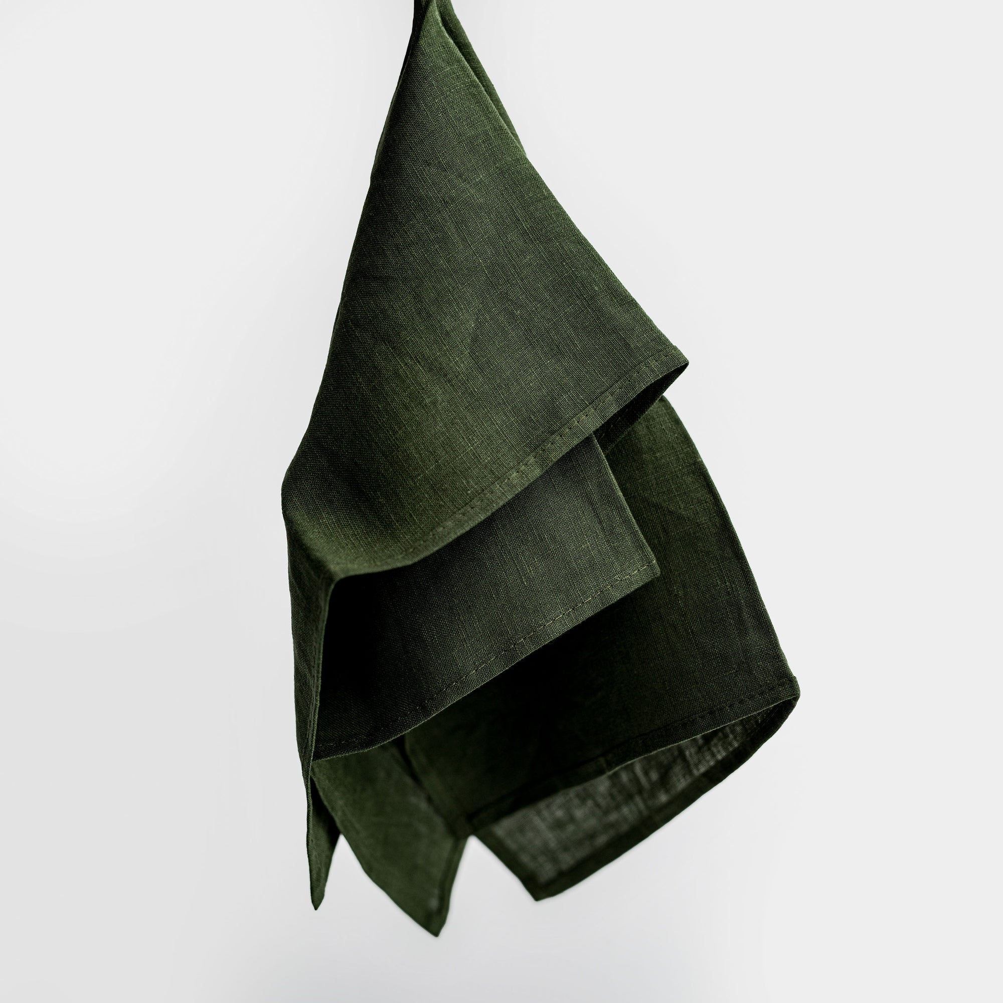 A green linen kitchen towel is featured, hung on a white background. 