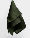 A green linen kitchen towel is featured, hung on a white background. 