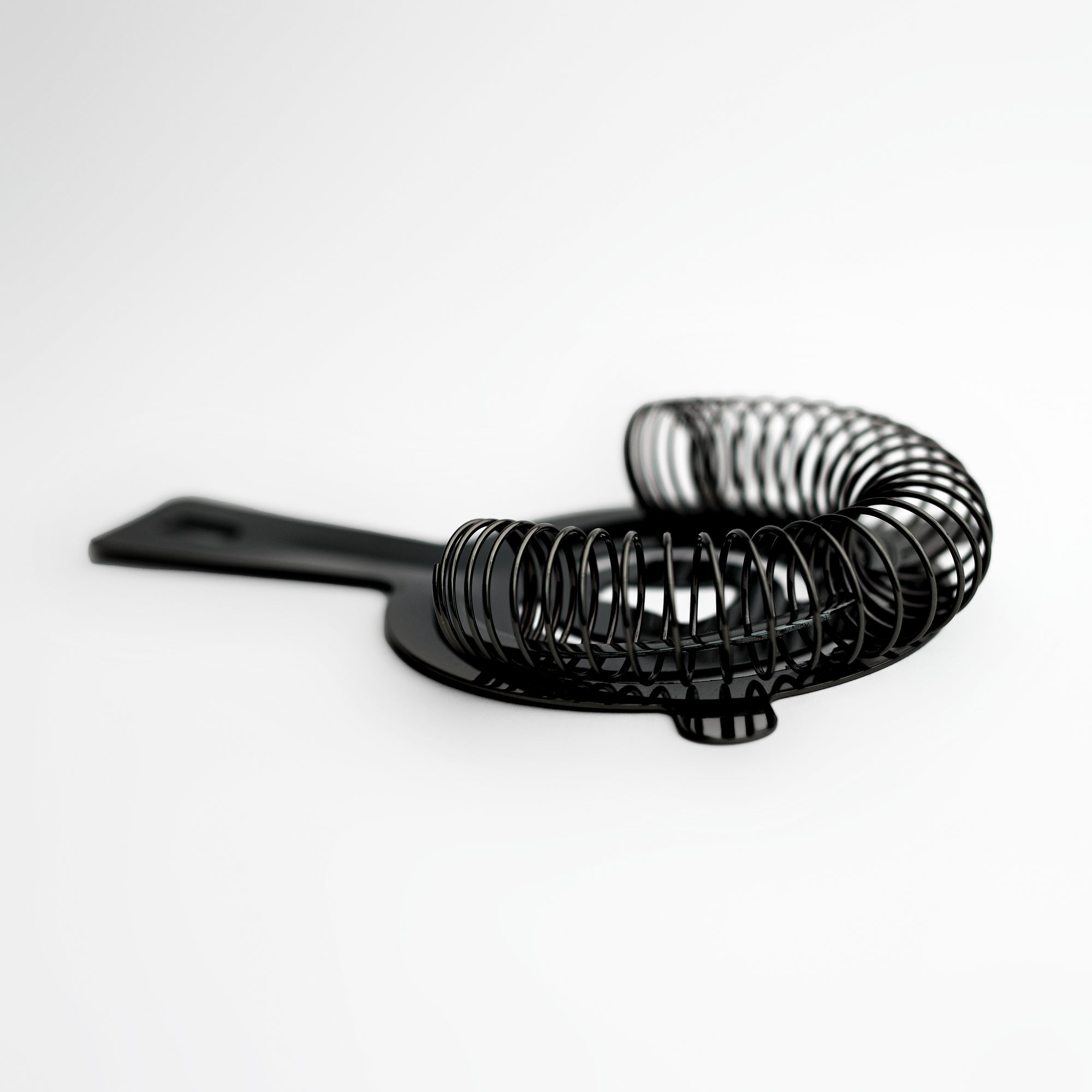 Gunmetal cocktail strainer side image on a white background. 