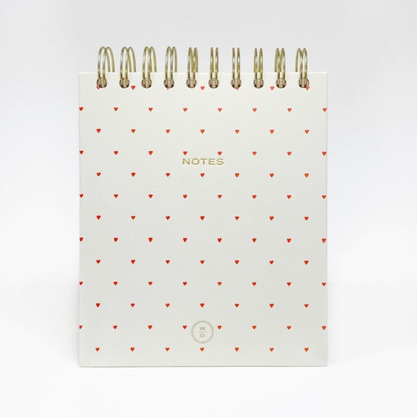 Hearts spiral notepad is featured white with red hearts in the cover with a gold spiral bound on top and notes printed ona white background. 