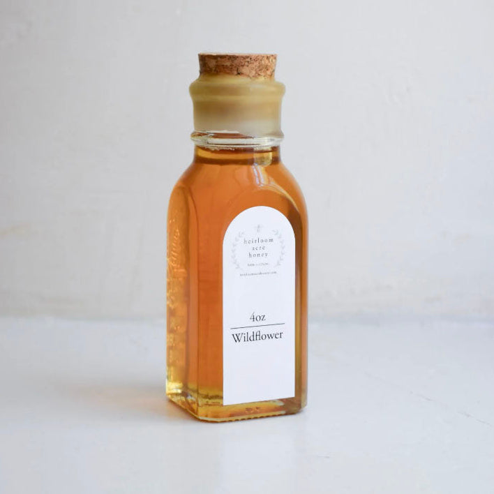 Heirloom Acre Raw Wildflower Honey 40 oz glass jar with a cork lid and cream label, centered on a clean white background.