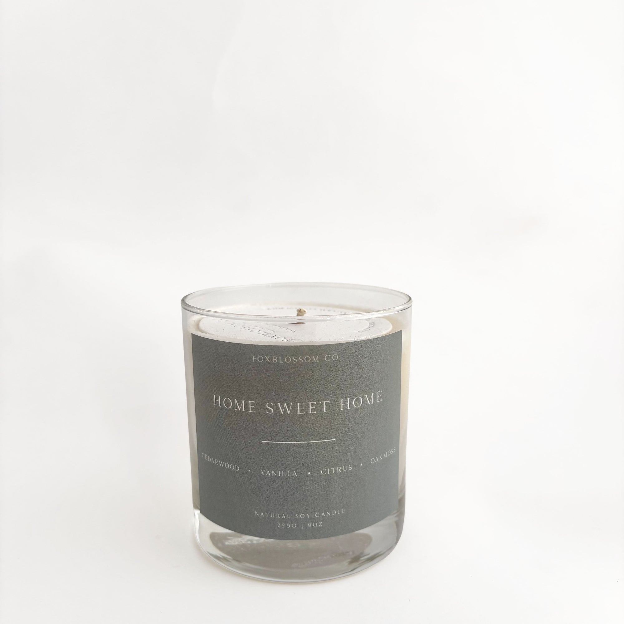 A soy candle in a clear glass jar with a dark gray label reading 'HOME SWEET HOME' and 'FOLKBLOSSOM CO.' on a clean white background.