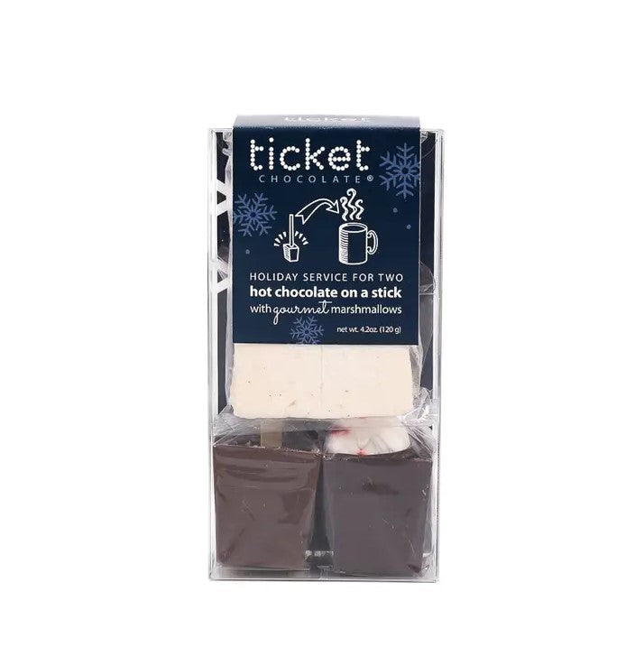 Hot chocolate on a stick by Ticket Chocolate, The two dark chocolate squares, square-shaped portions, likely designed to melt in hot liquid. The gourmet marshmallows are a pale beige. The header displays "ticket" in a stylized font, with "CHOCOLATE®" beneath it, and the product description "HOLIDAY SERVICE FOR TWO hot chocolate on a stick with gourmet marshmallows" in a contrasting font. The illustrations on the header show how to prepare the product by dropping it into a mug.