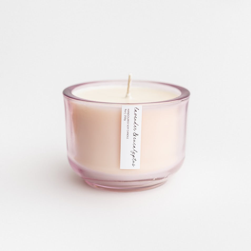 Lavender and Eucalyptus luxury candle is featured in its pink glass container on a white background. 