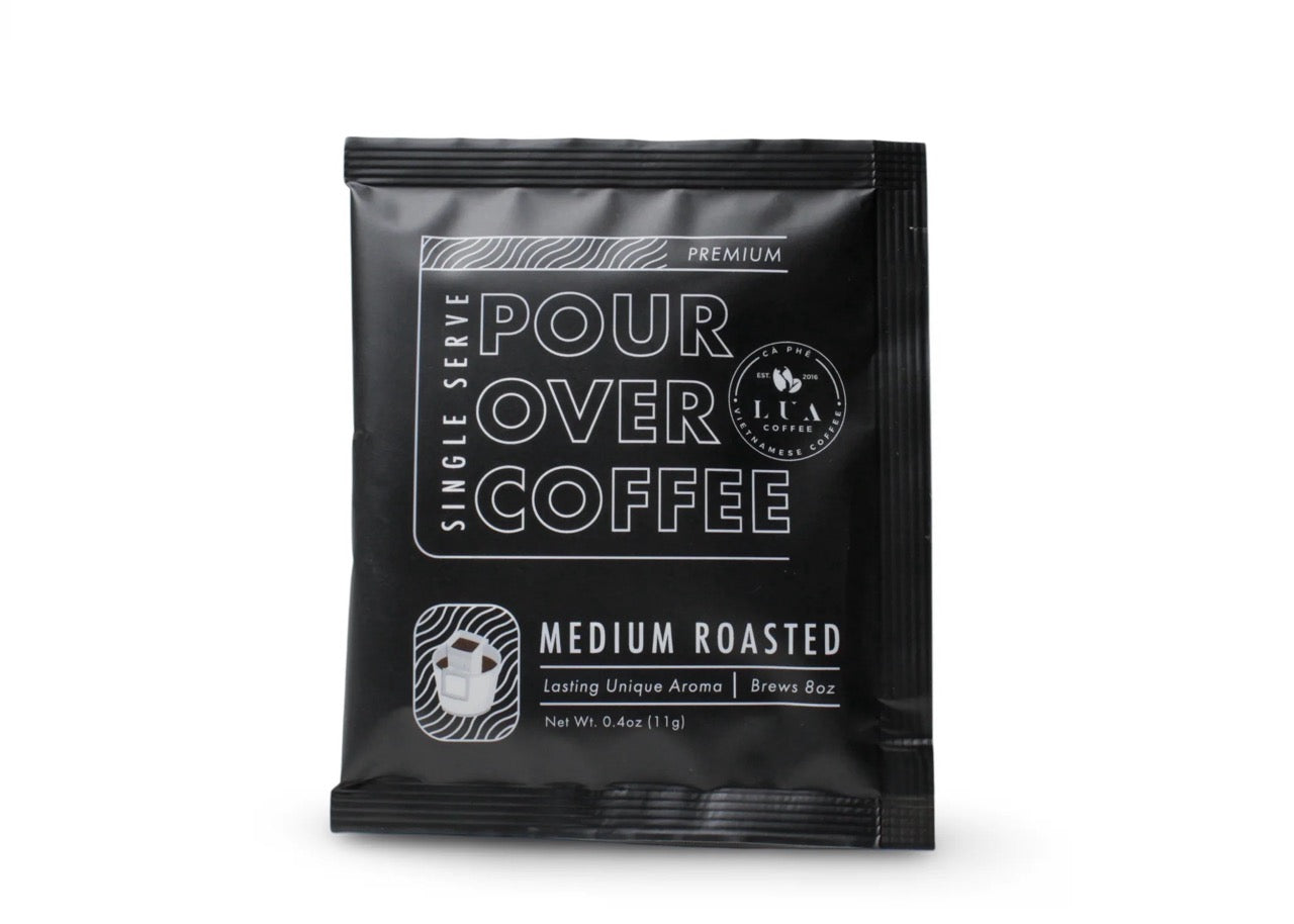 Lua Pour single serving over coffee in its black packaging on a white background.