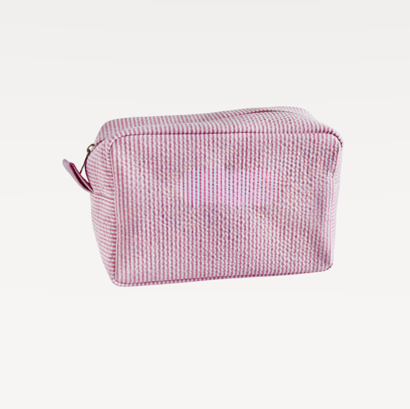 Pink textured toiletry bag with a zipper on a white background