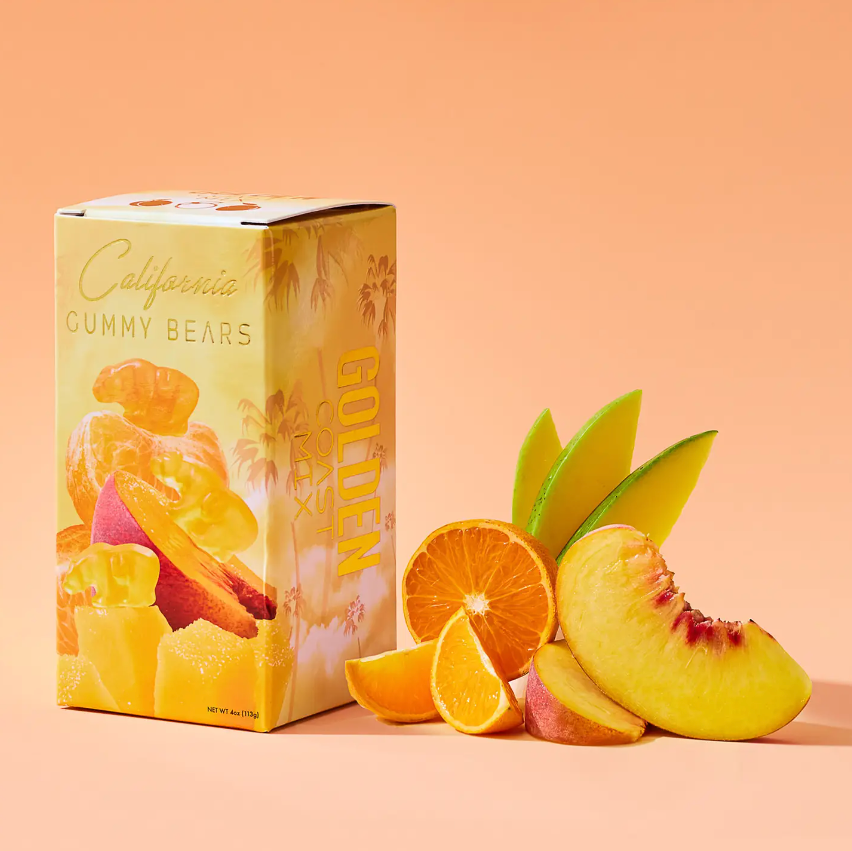 Box of California Gummy Bears with sliced oranges and peaches on a peach background