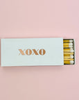 White matchbox with metalic rose gold lettering XOXO, includes matches with white tip. 