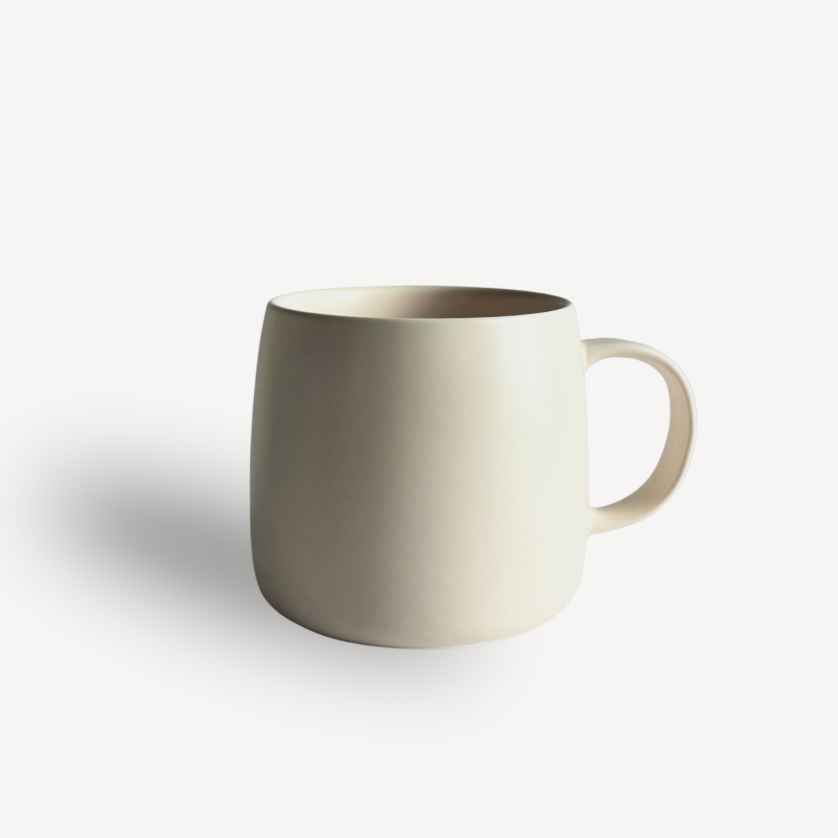 Glossy matte cream ceramic coffee mug with a curved handle, shown on a plain white background.