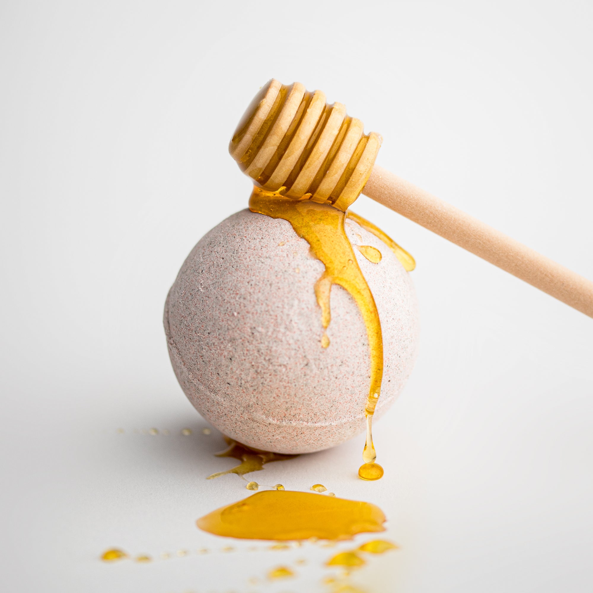 Milk and Honey Bath Bomb featured with honey drizzled on top and dripping, displayed on a white background.