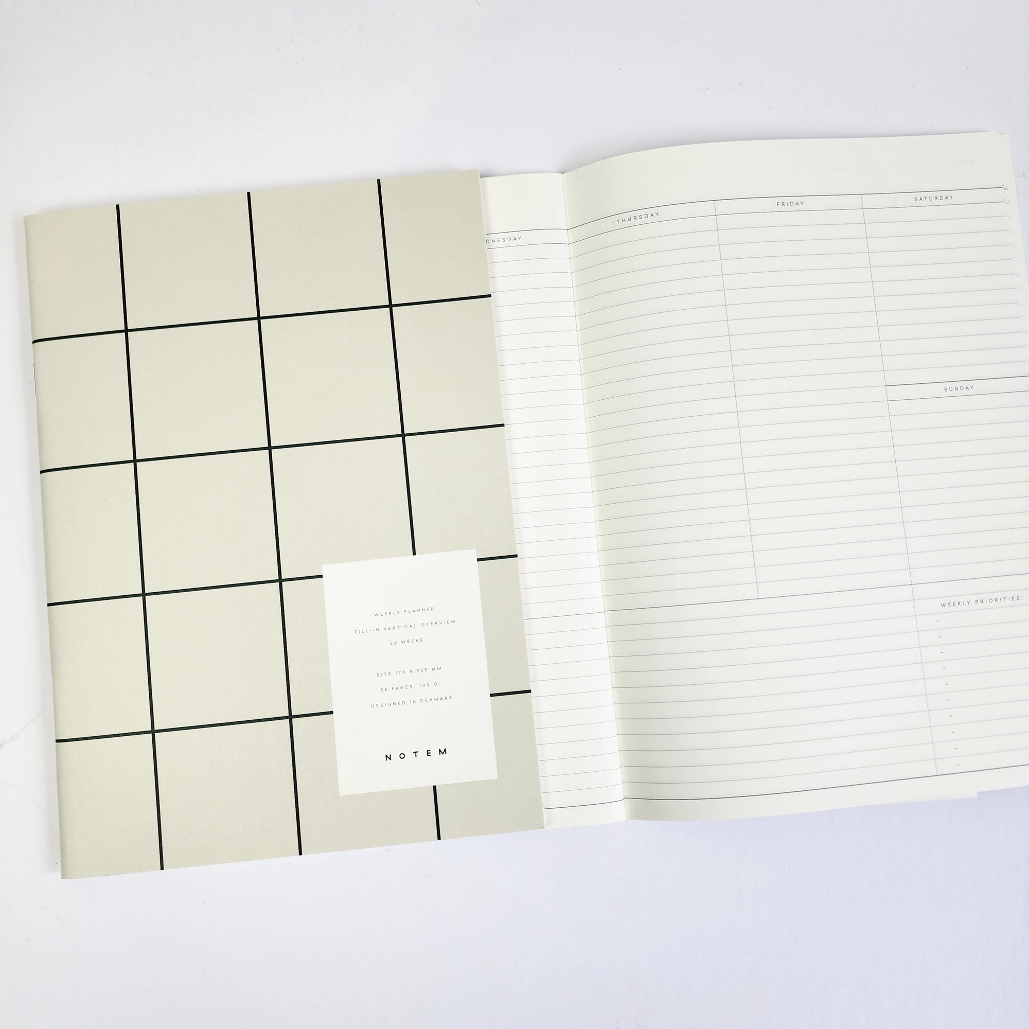 over featured, a rectangular planner, its surface marked by a dark gray grid over a pale beige background. Positioned on the lower right, a white rectangular label provides details of the planner in black lettering.
Showing one of the pages inside of the planner.